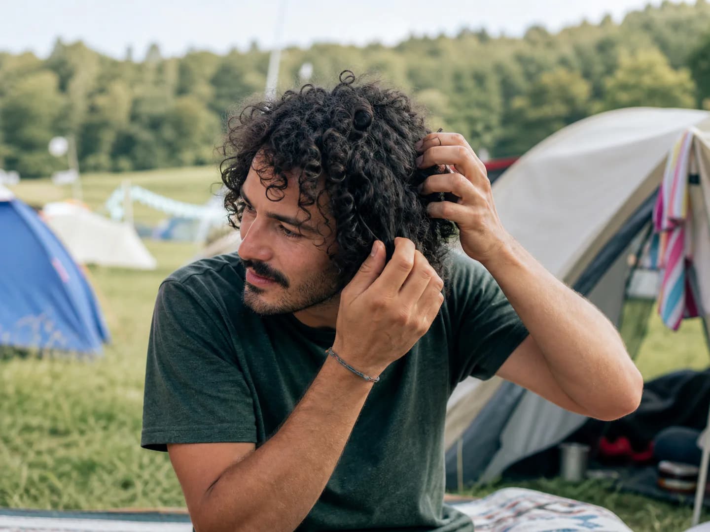 Man refreshing his curly hair at a music festival campsite